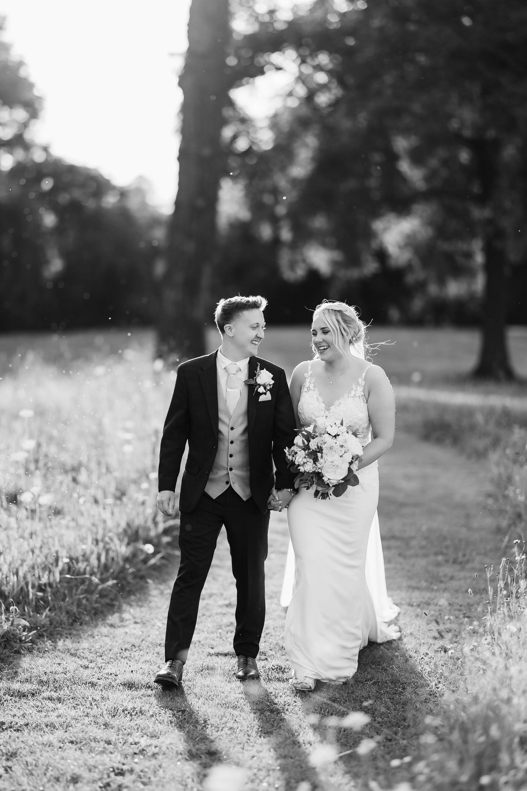 Bride and groom walking on path through field