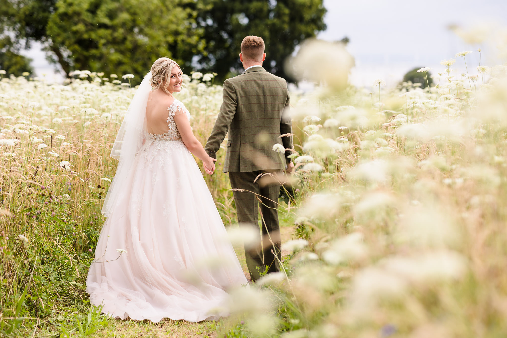 Wedding couple walking through the wildflower meadow at St Tewdrics House